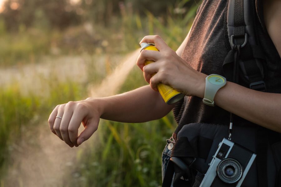 woman-using-anti-mosquito-spray-outdoors-at-hiking-trip